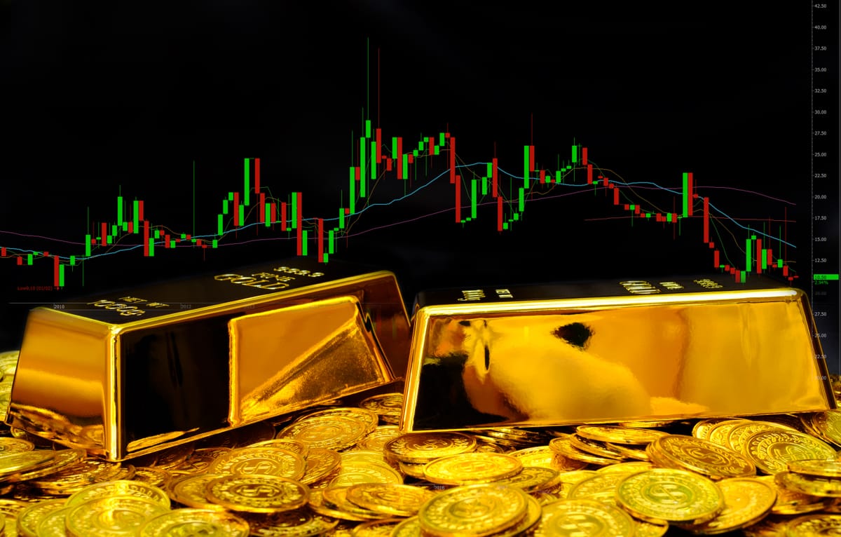Gold bullion and coins positioned in front of a technical analysis candlestick chart showing market volatility.